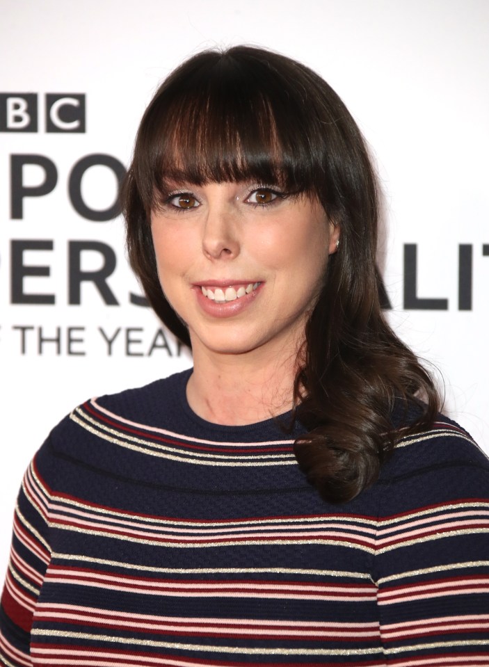 a woman in a striped sweater smiles in front of a bbc poster