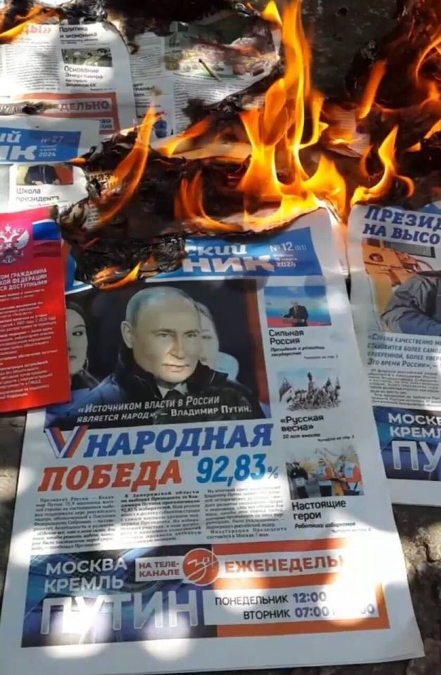 A Russia newspaper bearing Putin's face is set on fire by a Mavka operative