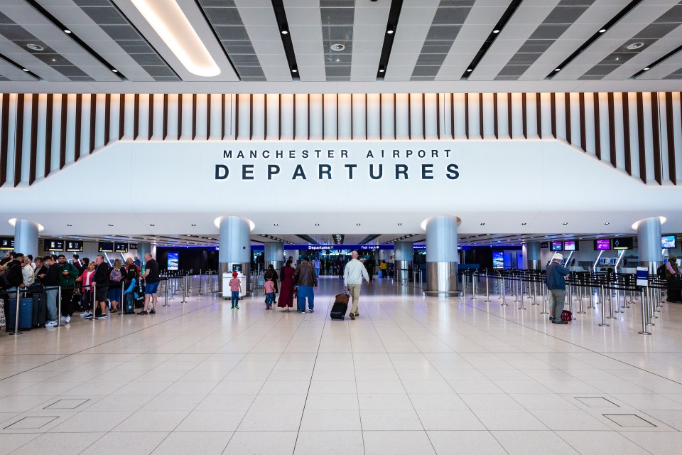 a sign for manchester airport departures is above a crowd of people