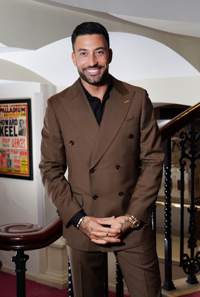 a man in a brown suit stands in front of a palladium poster