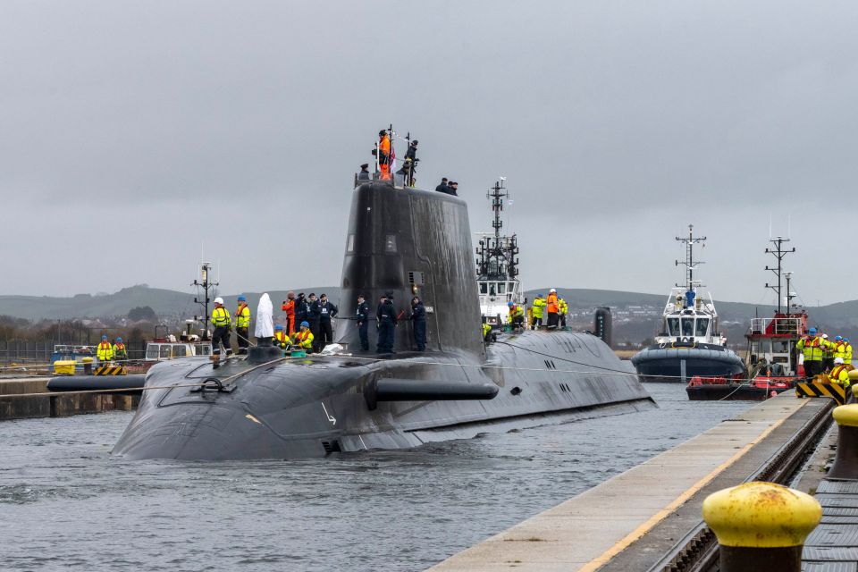 a submarine is docked at a dock with people on the deck