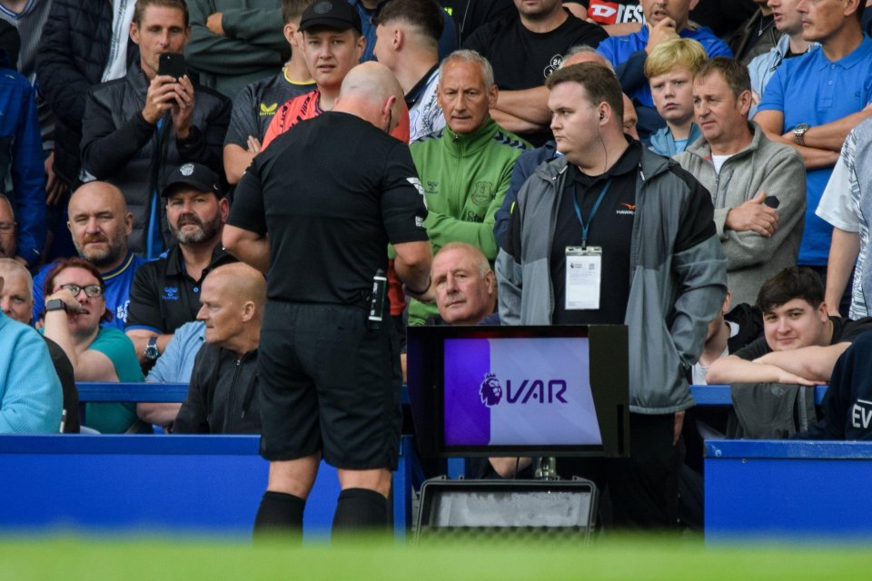 a referee stands in front of a screen that says var