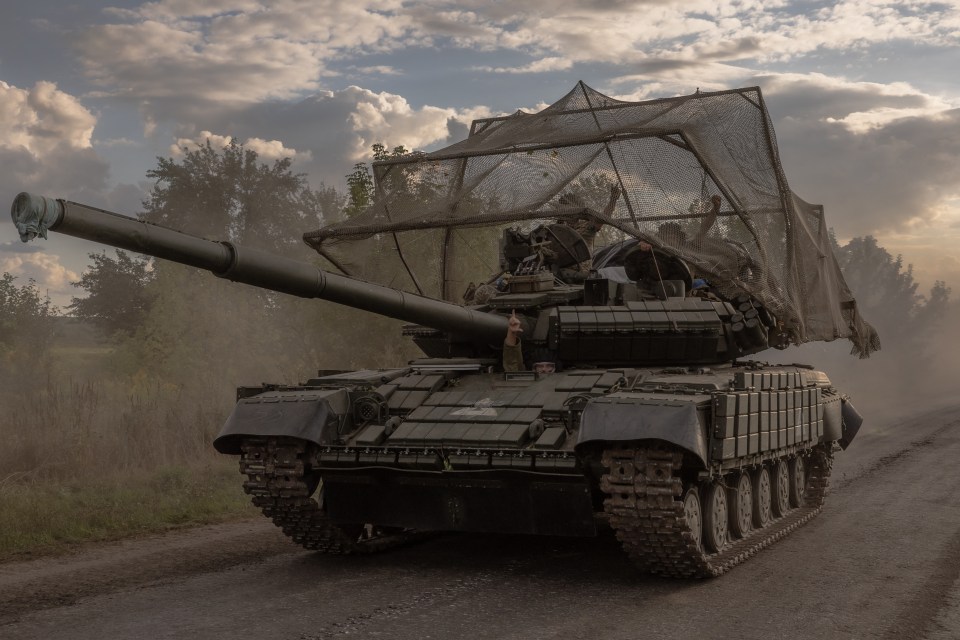 a military tank is driving down a dirt road