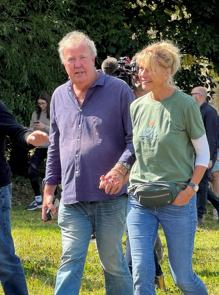 a man in a blue shirt and a woman in a green shirt are walking in a field