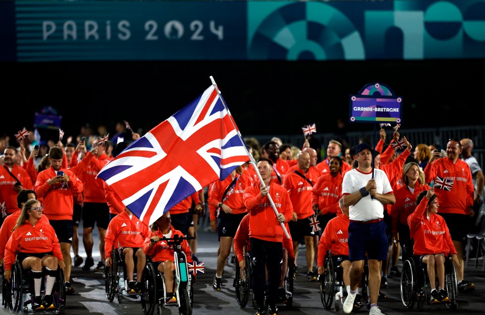 a group of people marching in front of a sign that says paris 2024