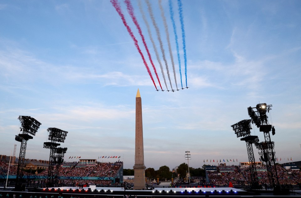 red white and blue jets fly over an obelisk