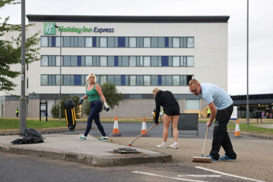 People clean up outside the Holiday Inn Express hotel after rioters attacked the building in Rotherham