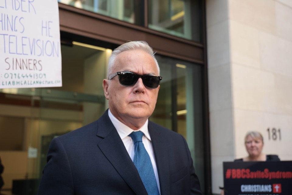 a man wearing sunglasses stands in front of a sign that says sinners