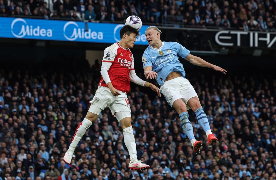 two soccer players going for the ball in front of an ad for midea