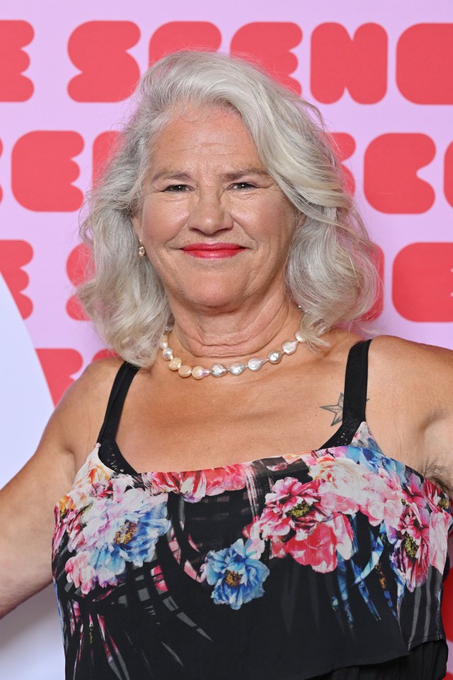 a woman wearing a floral dress and pearls smiles for the camera