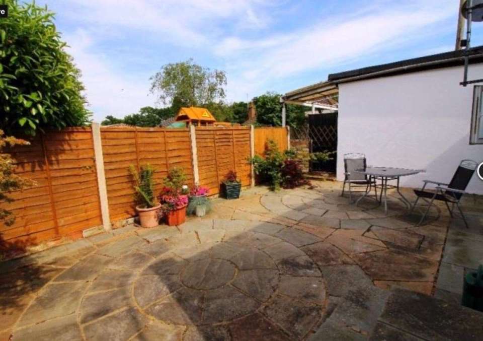 a backyard with a wooden fence and a table and chairs