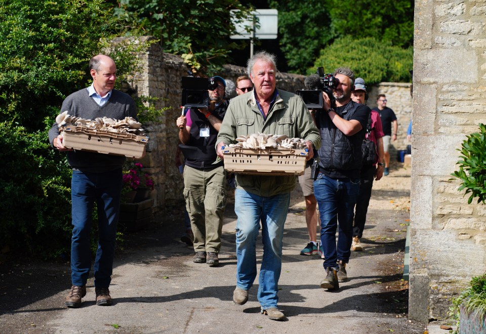 a man carrying a crate of mushrooms is being followed by two other men