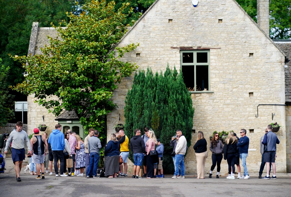 a group of people are standing outside of a stone building