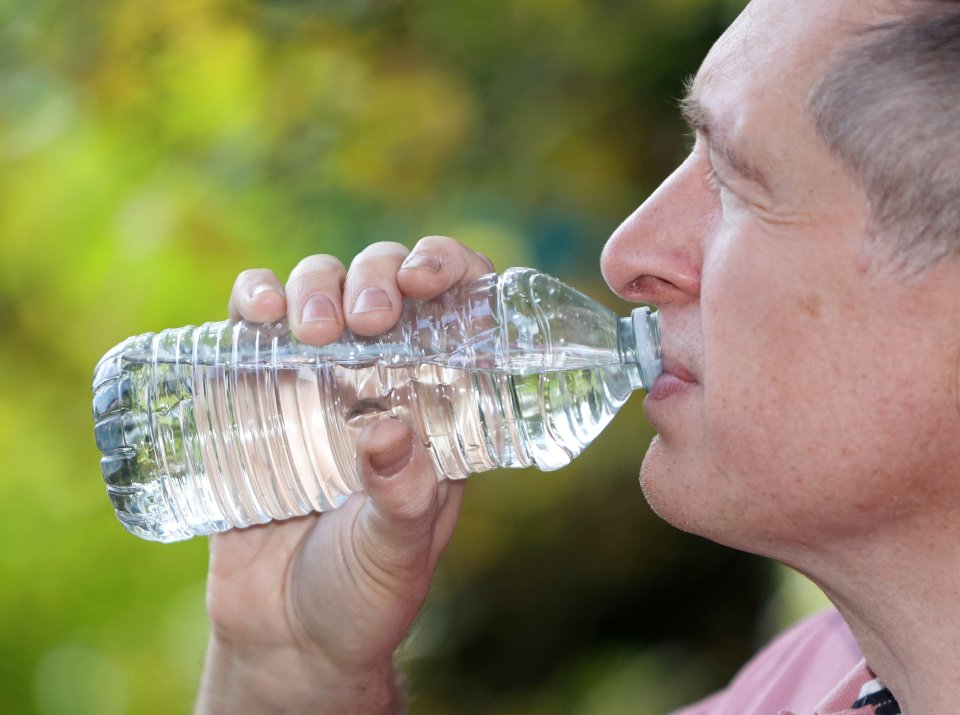 a man is drinking water from a plastic bottle