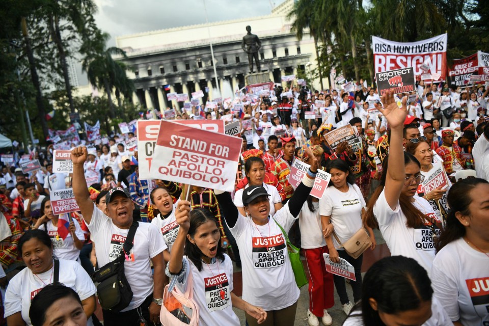 a crowd of people holding up signs including one that says " stand for pastor quiboloy "