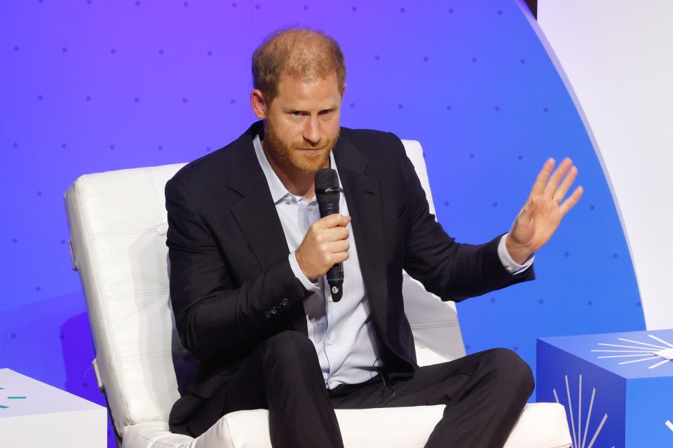 a man in a suit is sitting in a chair holding a microphone