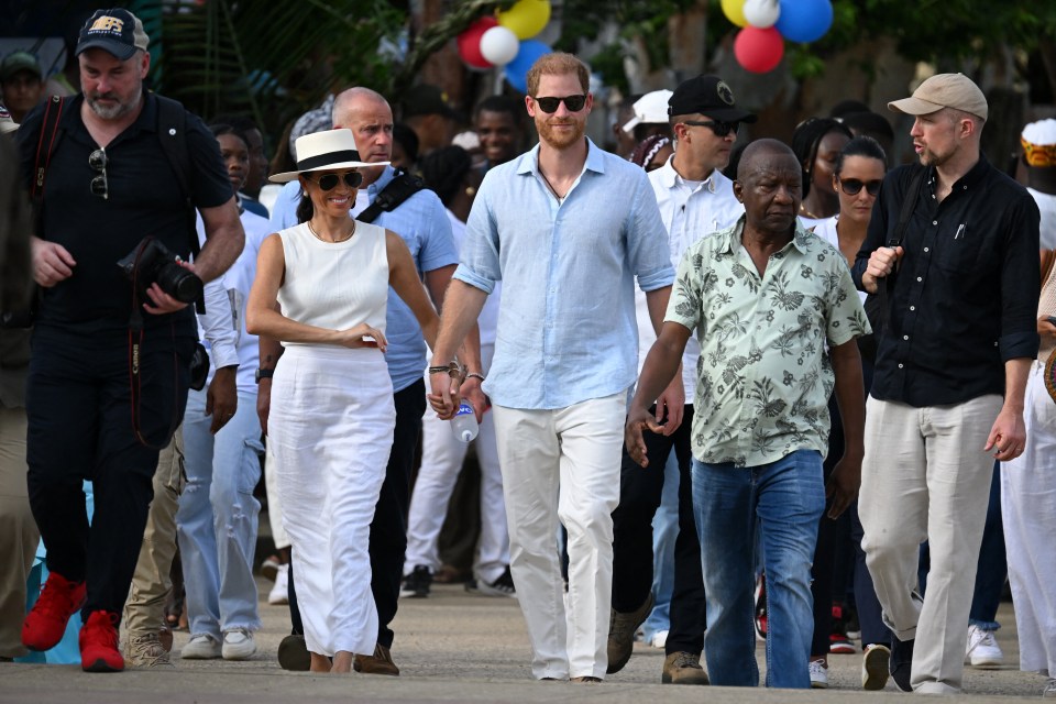 a group of people are walking down a street and one of them is wearing a hat