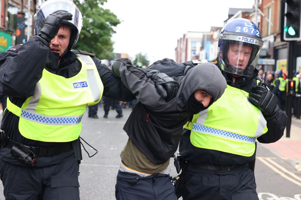 A protester being leg away by riot police in Middlesbrough