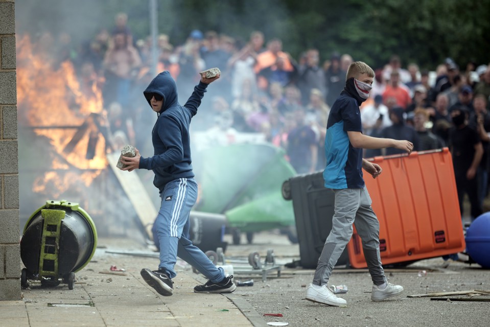 a man wearing a mask throws a rock at a fire