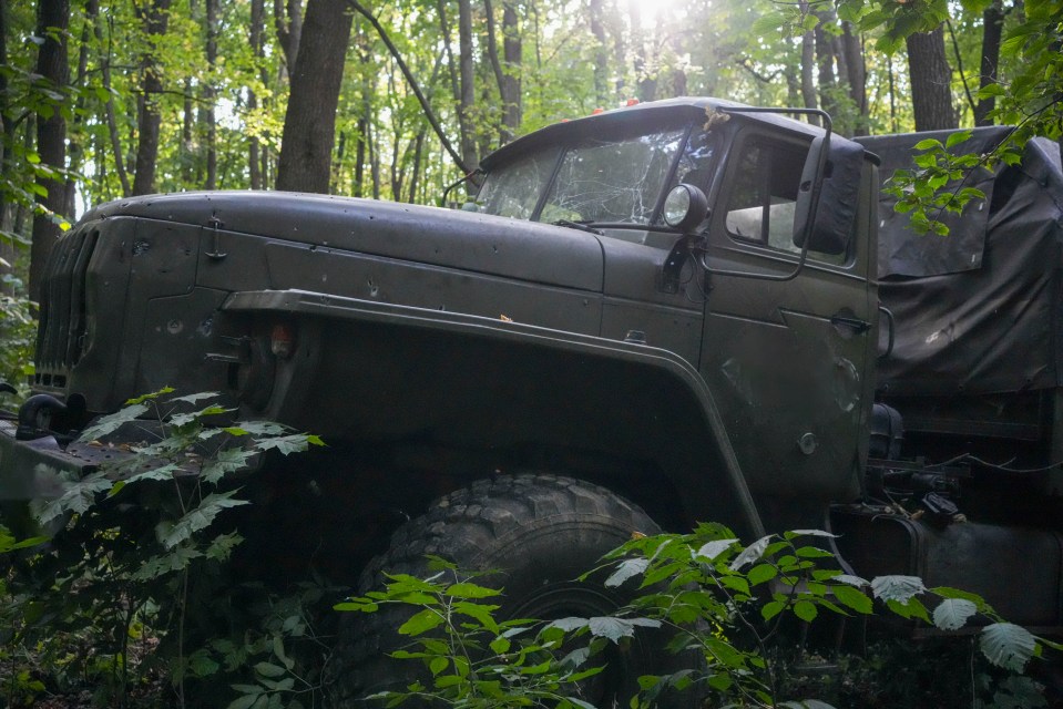 a military vehicle is sitting in the middle of a forest