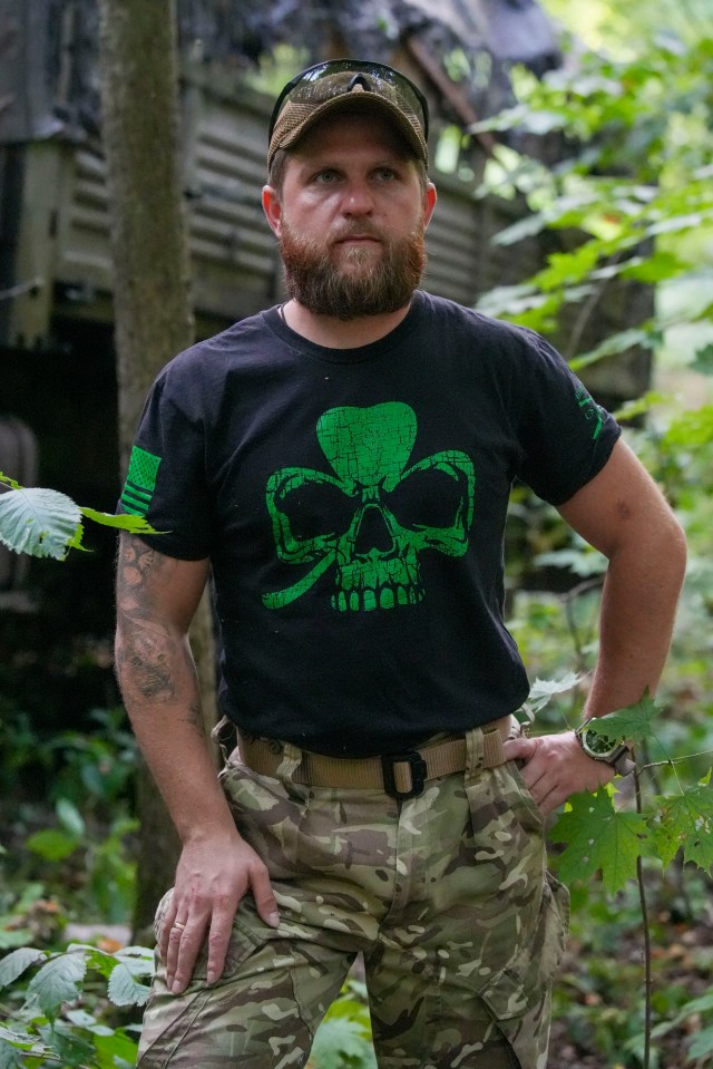 a man wearing a black shirt with a green skull on it