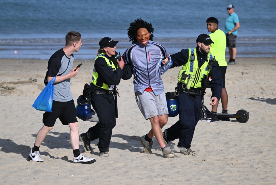 Police officers detain a protester who broke through the police line in Weymouth