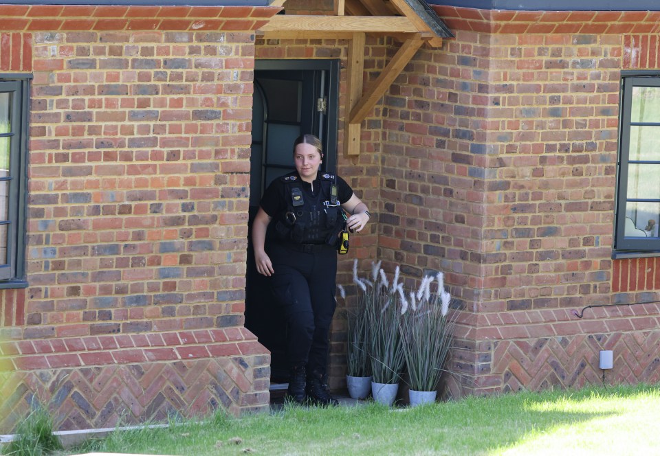 a police officer stands in the doorway of a brick house