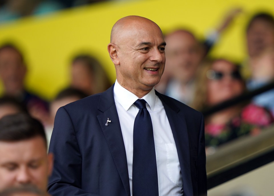 a bald man in a suit and tie smiles in front of a crowd