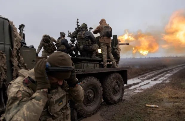 a group of soldiers are riding on the back of a military vehicle .