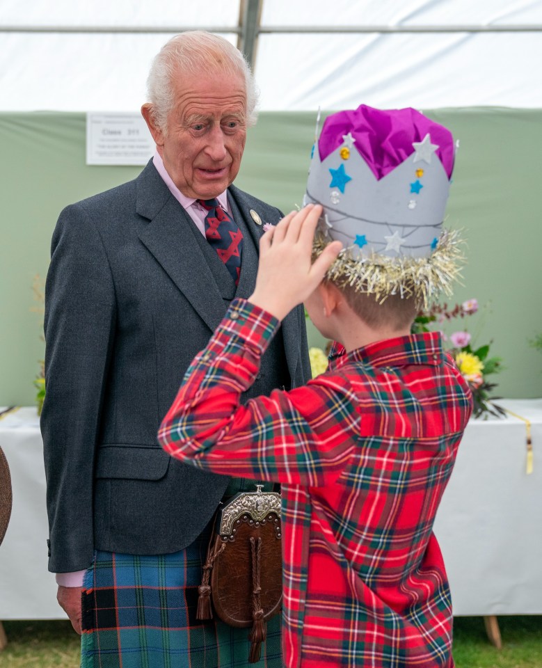 King Charles smiles as he spots Oliver Keith's paper crown