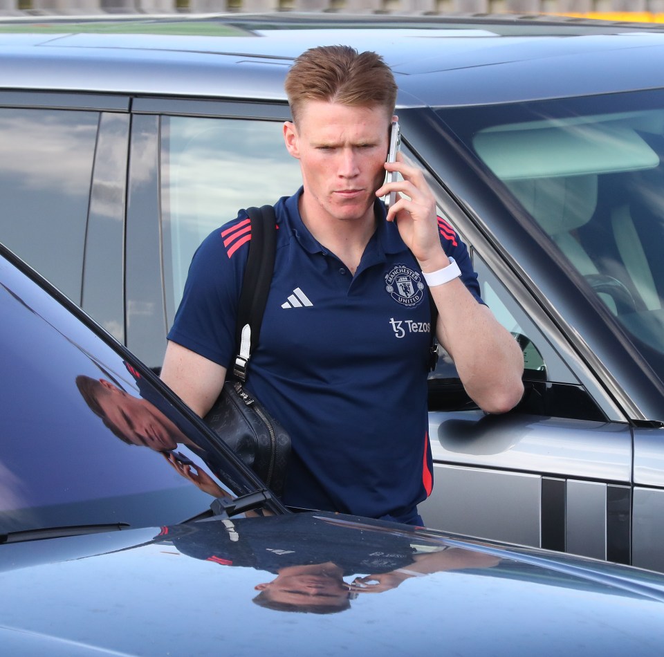 a man wearing a shirt that says manchester united is talking on a cell phone