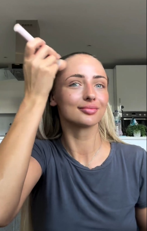 a woman in a blue shirt is applying makeup to her face