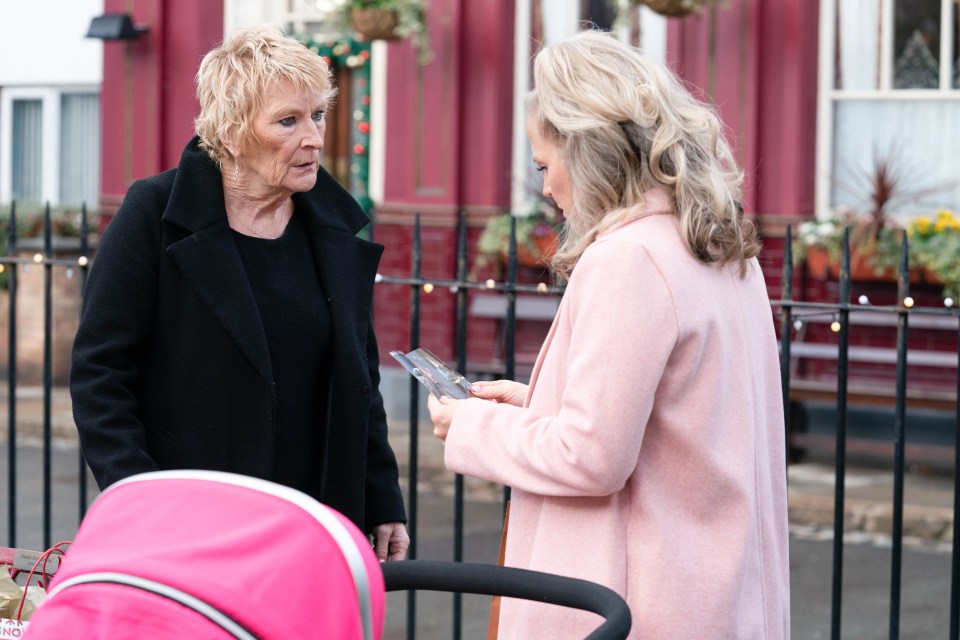 a woman in a pink coat is talking to an older woman in a black coat