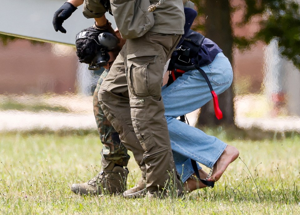 The suspect crouching over under cops in Germany