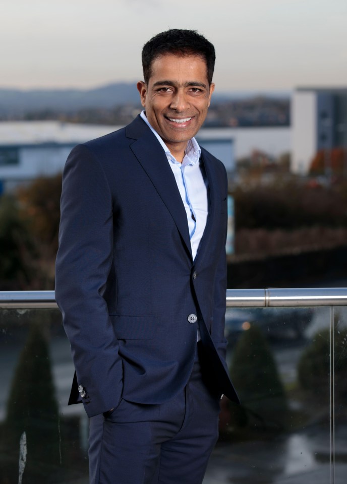 a man in a suit stands on a balcony with his hands in his pockets