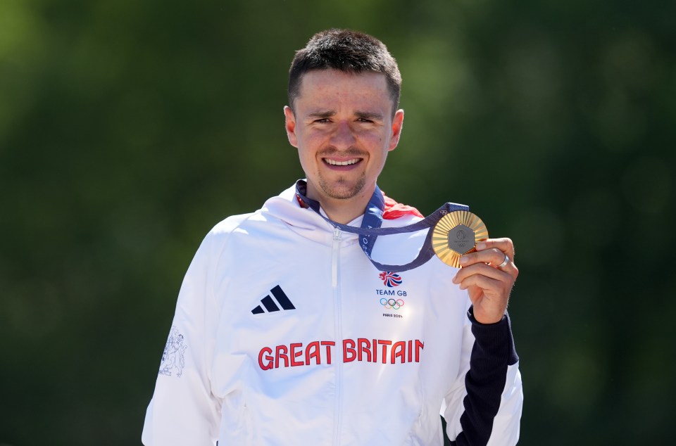 a man wearing a great britain jacket holds a gold medal