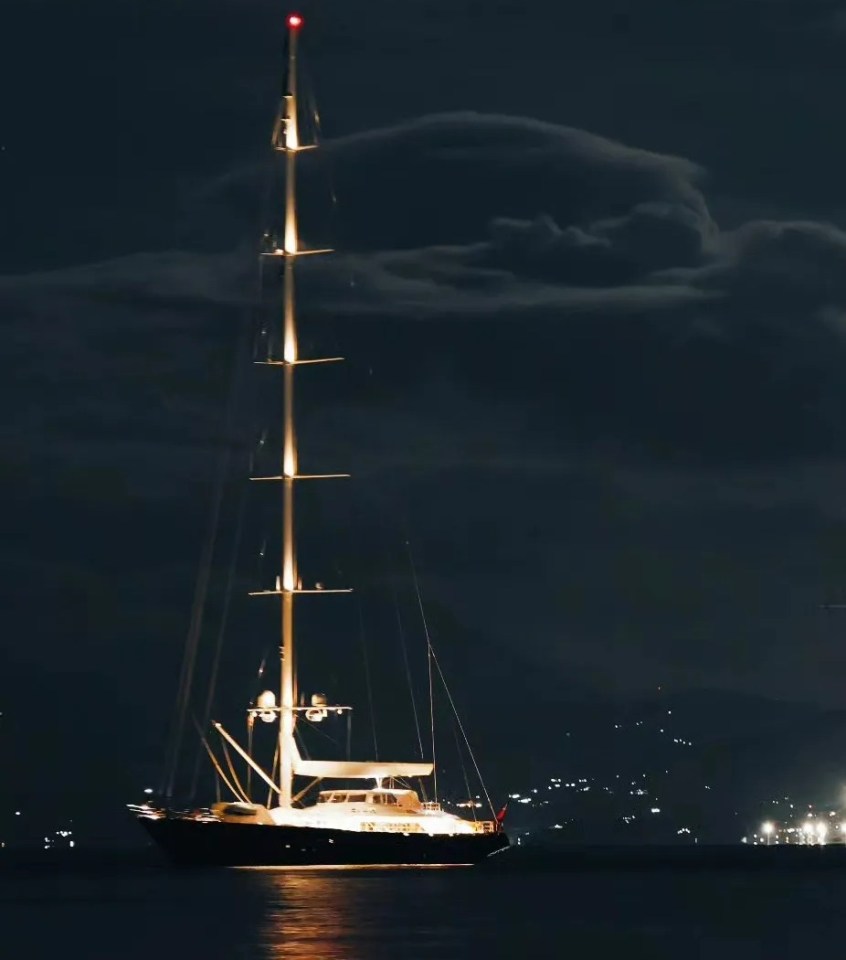 two sailboats are in the water at night with mountains in the background