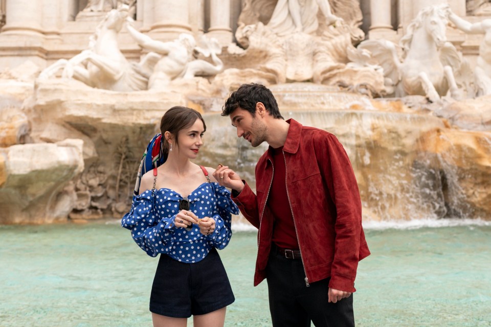 a man and a woman are standing in front of a fountain