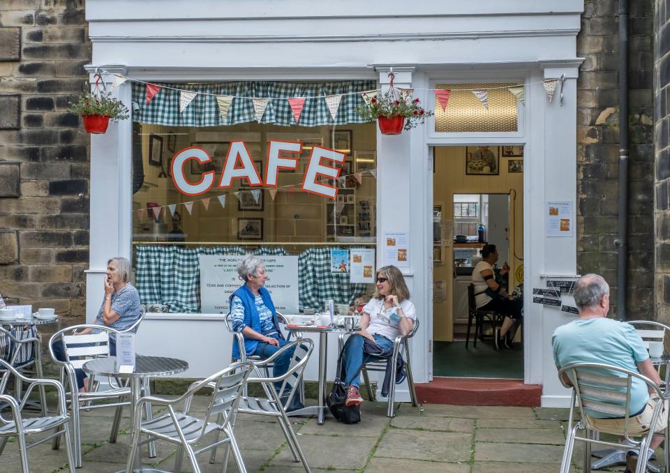 people sit at tables outside of a cafe