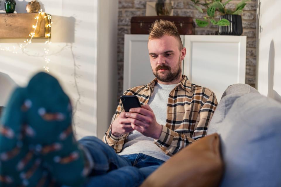 a man laying on a couch looking at his phone