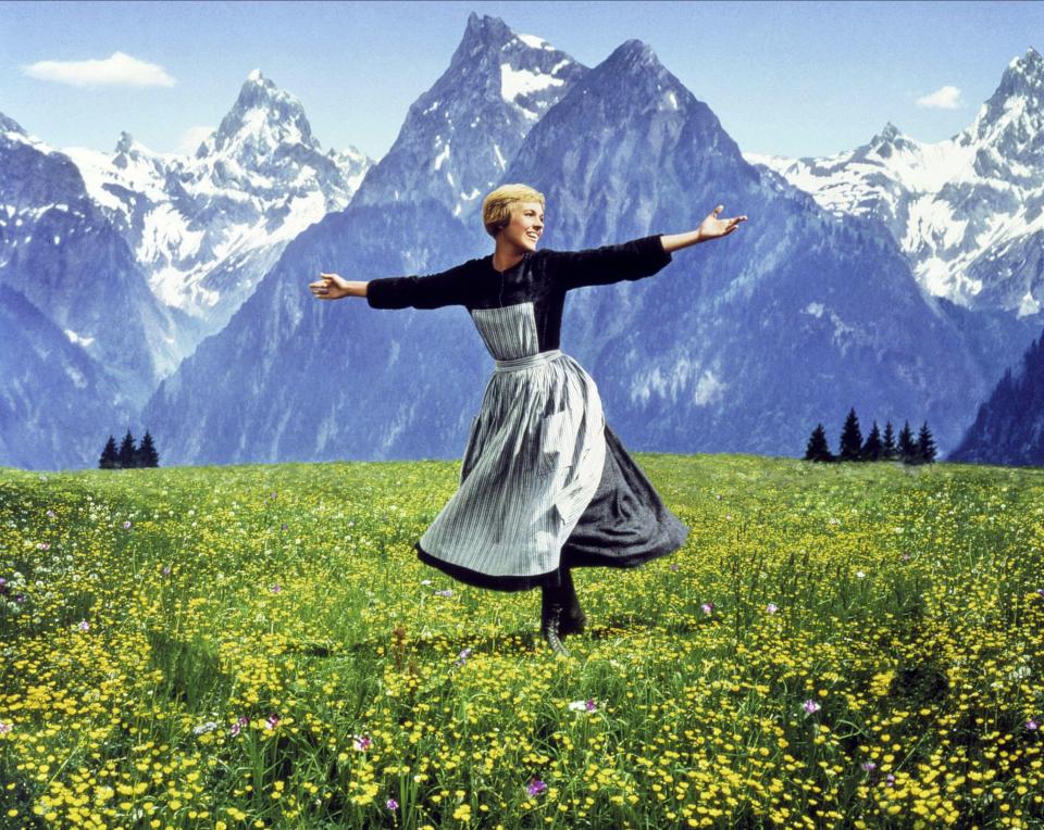 a woman is dancing in a field with mountains in the background