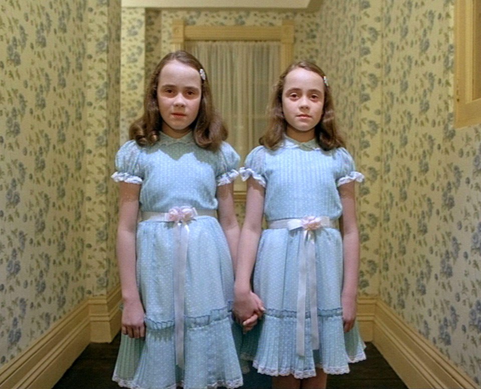 two girls in blue dresses are holding hands in a hallway