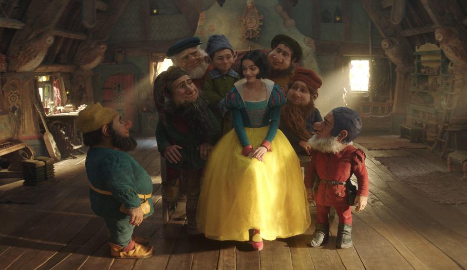 snow white is surrounded by a group of dwarfs