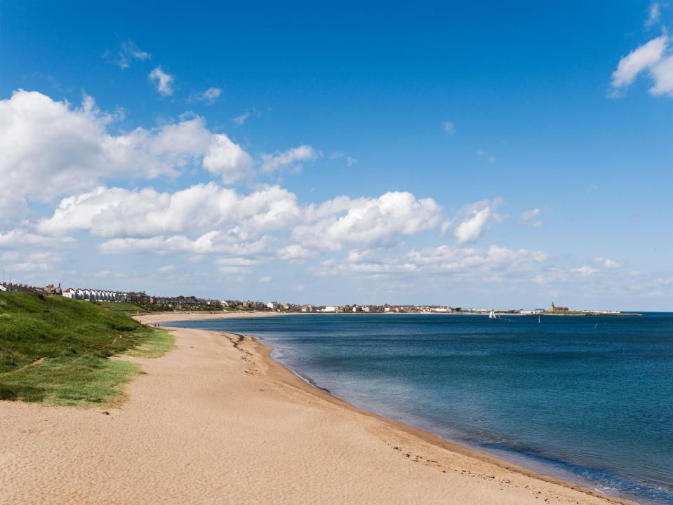 a beach with a blue sky and white clouds in the background