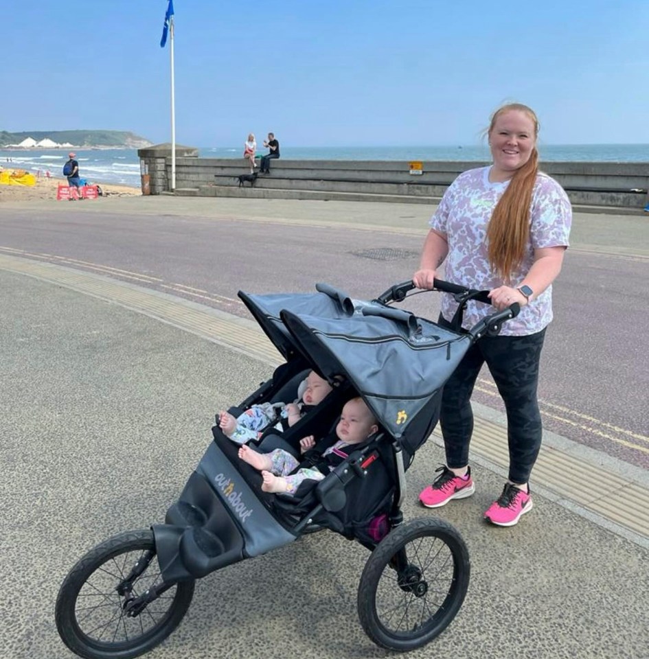 a woman pushes a stroller with two babies in it