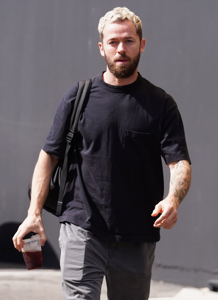 a man in a black t-shirt is holding a cup of coffee