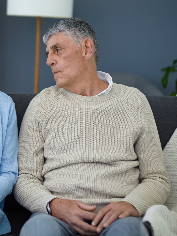 a man and a woman sit on a couch looking at each other