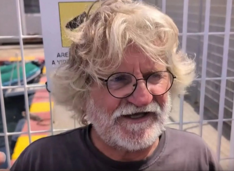 a man with glasses stands in front of a bbc sign