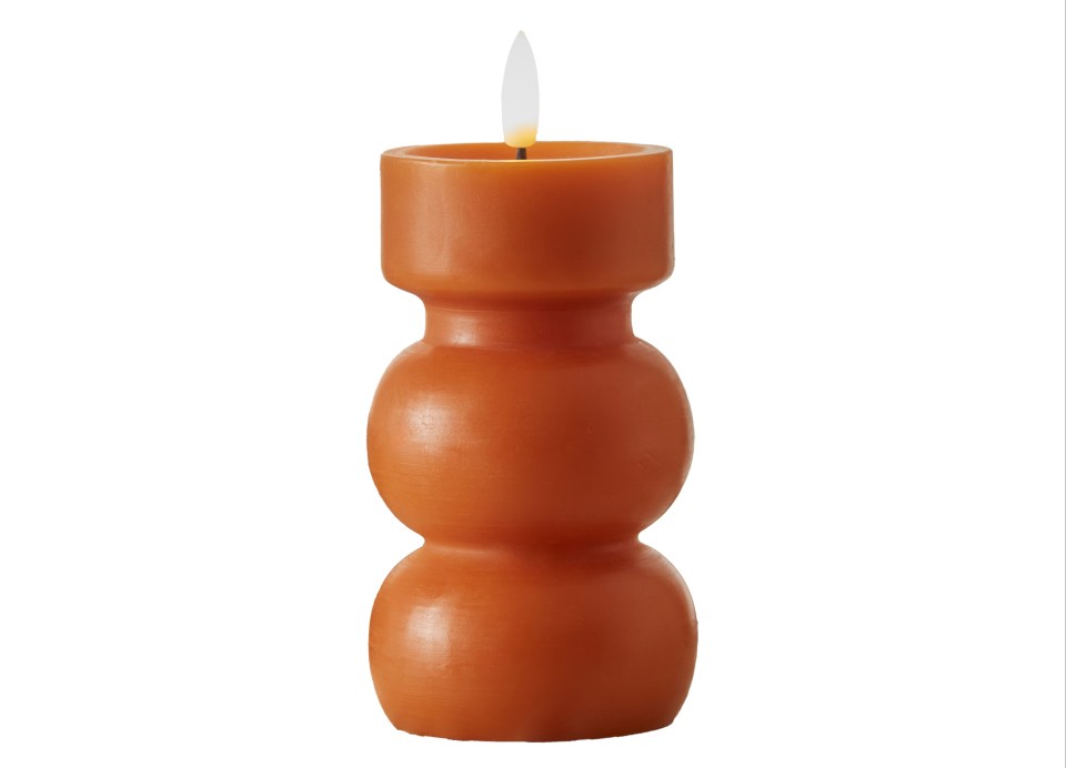 an orange candle with a white flame on a white background