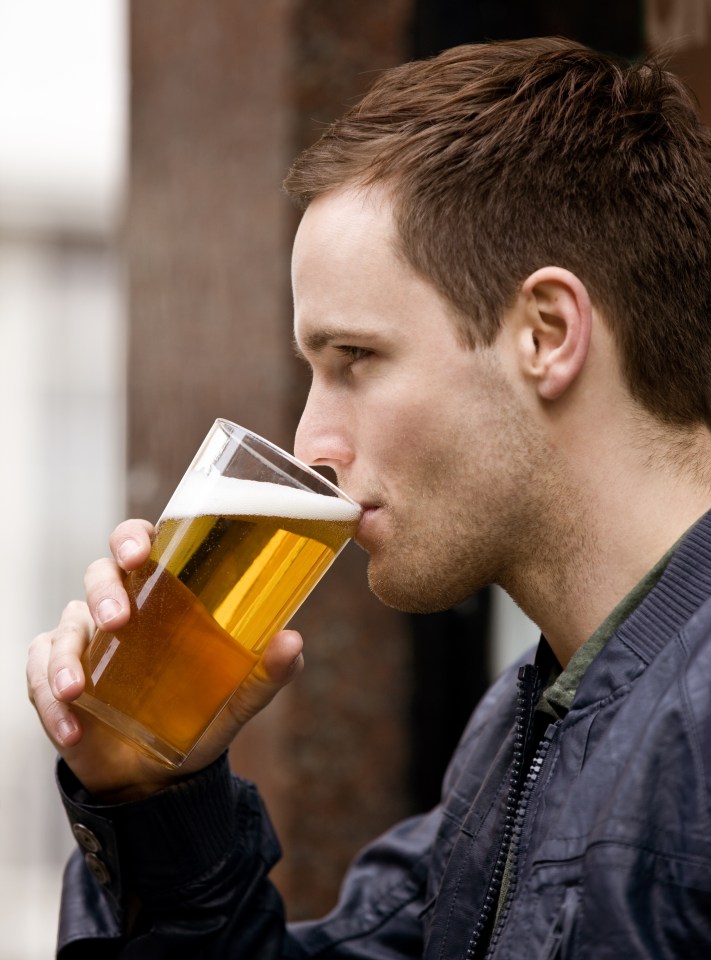 a man in a jacket is drinking a glass of beer